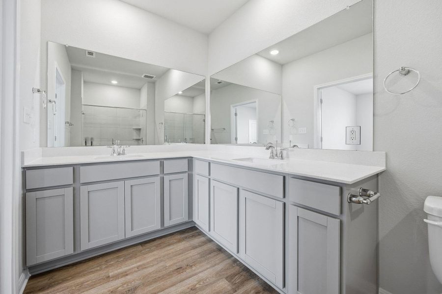 Bathroom with a stall shower, double vanity, and light wood-type flooring