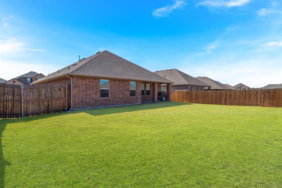 Back of house with a yard, a fenced backyard, a shingled roof, and brick siding