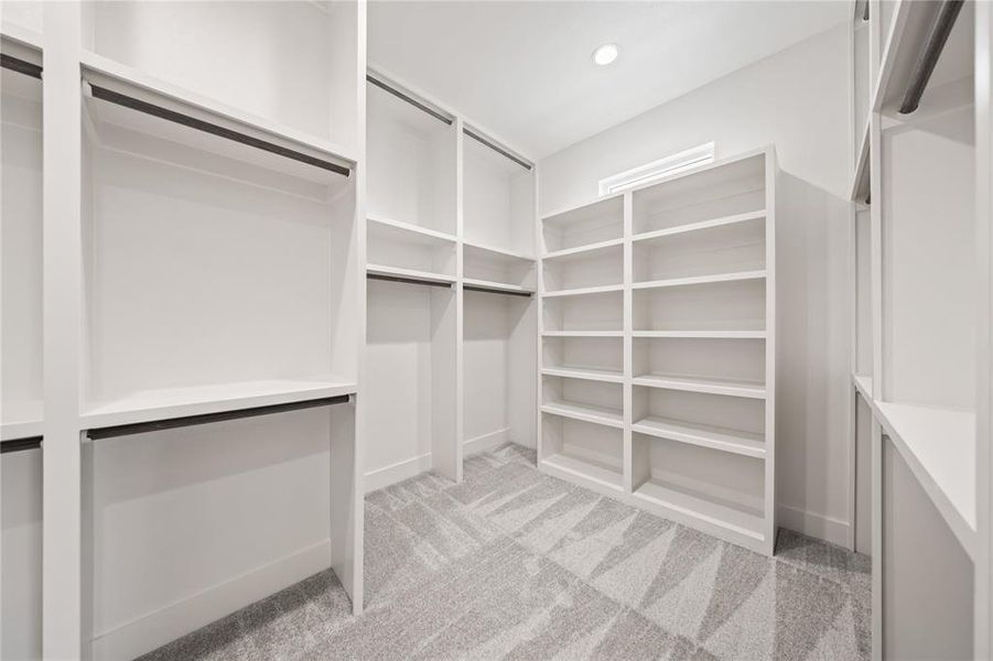 Custom built-in closet system featuring white shelving, hanging rods, and patterned carpet flooring