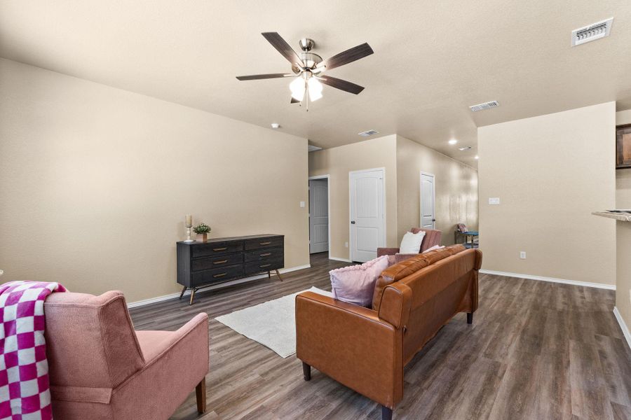 Living room featuring dark wood-type flooring, ceiling fan, and recessed lighting