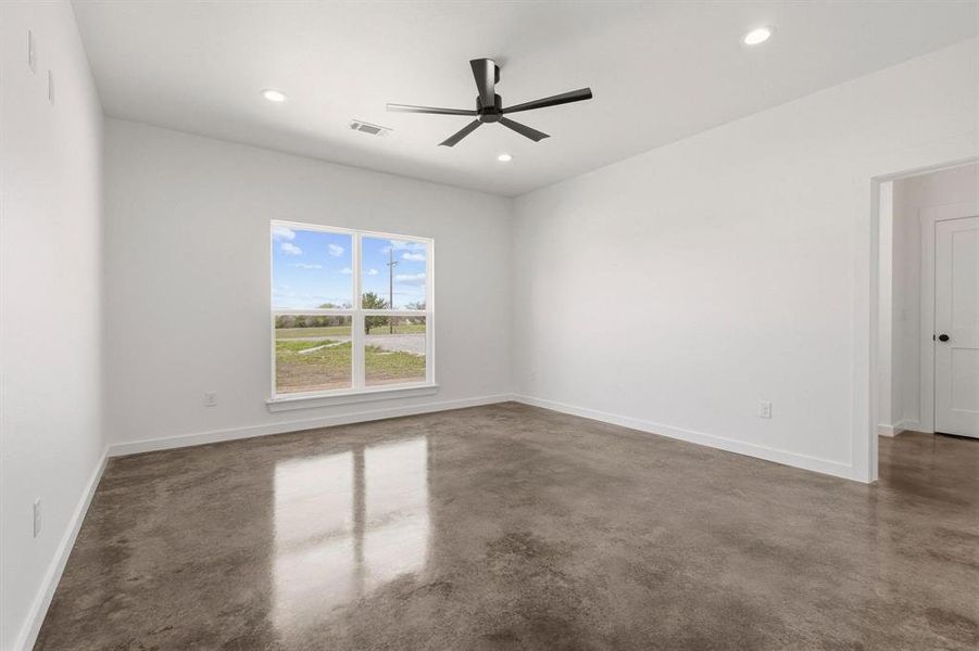 This room features polished concrete floors, a modern ceiling fan, and recessed lighting