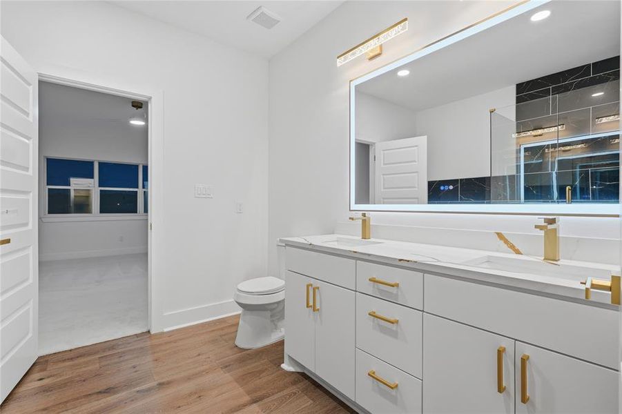 Dual vanity with white cabinetry, gold-finish hardware, and a white countertop with gold veining