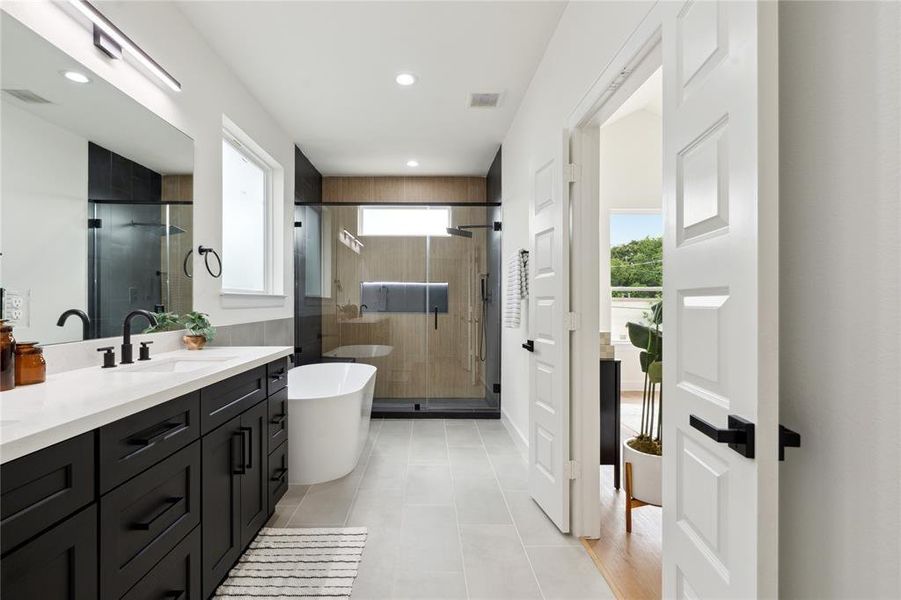 Sleek and modern bathroom featuring a spacious walk-in shower, elegant freestanding bathtub, and dual-sink vanity with stylish black cabinetry. Sleek and modern bathroom featuring a spacious walk-in shower, elegant freestanding bathtub, and dual-sink vanity with stylish black cabinetry.