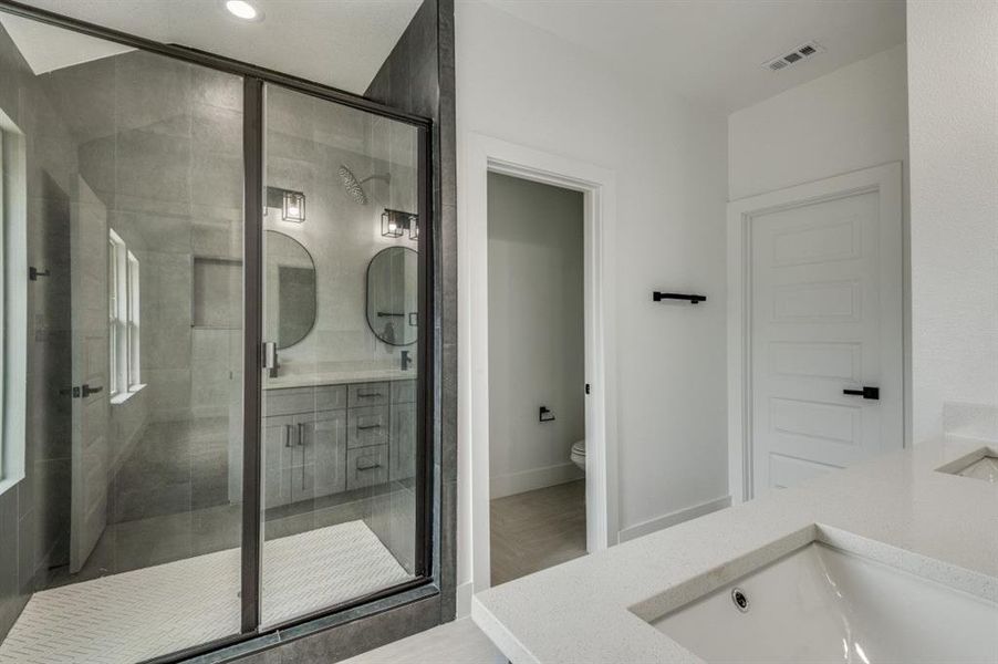 Bathroom featuring vanity, toilet, and an enclosed shower