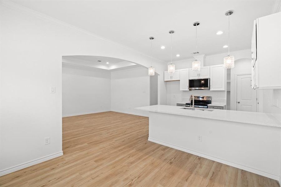 Kitchen featuring appliances with stainless steel finishes, recessed lighting, ornamental molding, white cabinetry, and arched walkways Kitchen featuring appliances with stainless steel finishes, recessed lighting, ornamental molding, white cabinetry, and arched walkways
