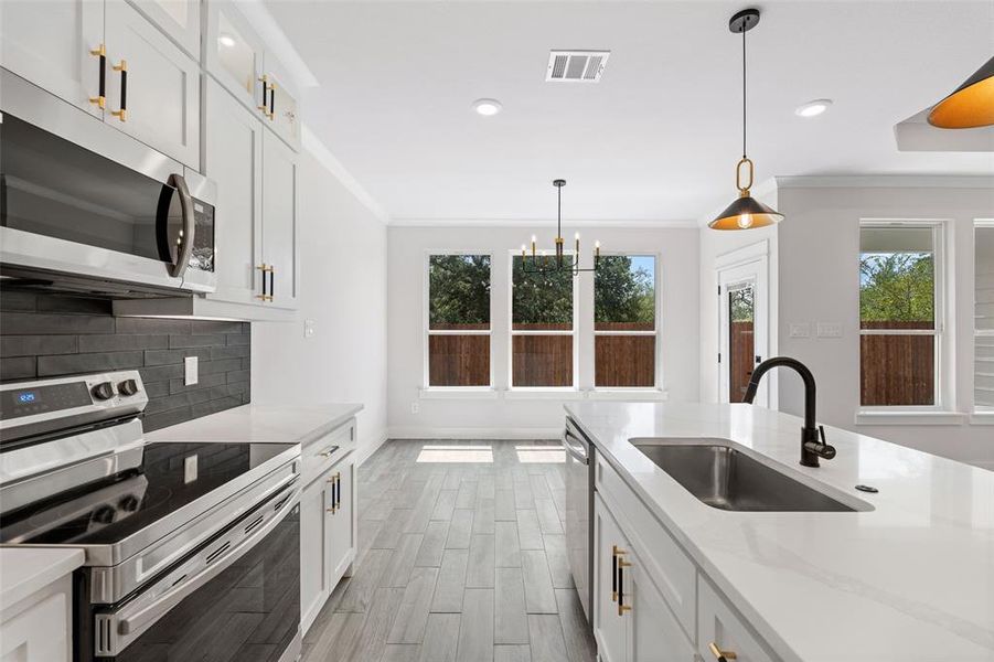 Kitchen featuring stainless steel appliances, sink, and white cabinetry