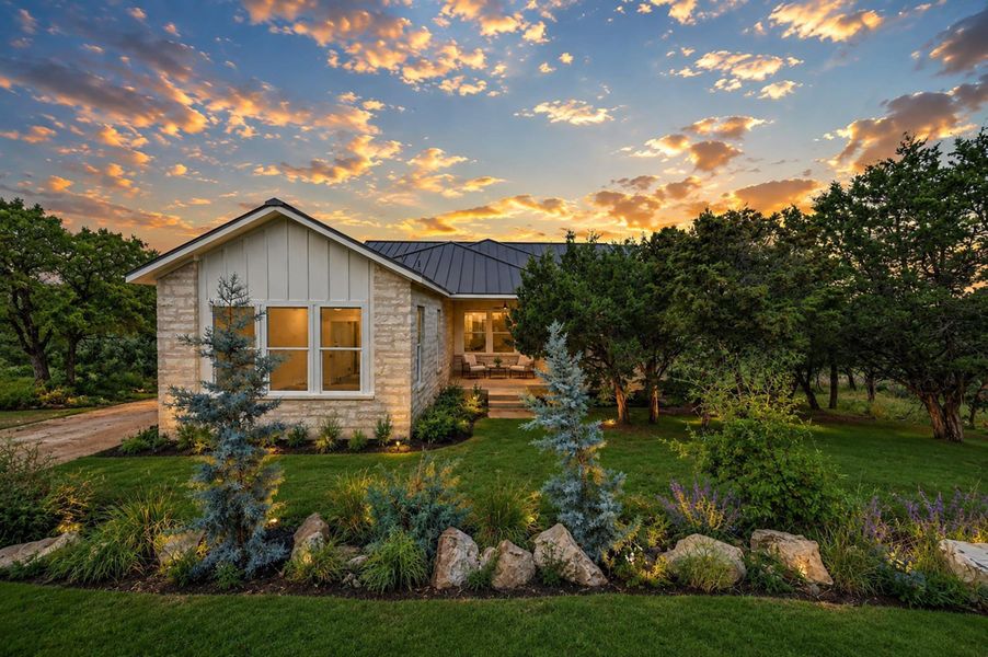 Dramatic sunset skies frame a modern stone exterior nestled among manicured lawns and native trees.Virtual Staging. Dramatic sunset skies frame a modern stone exterior nestled among manicured lawns and native trees.Virtual Staging.