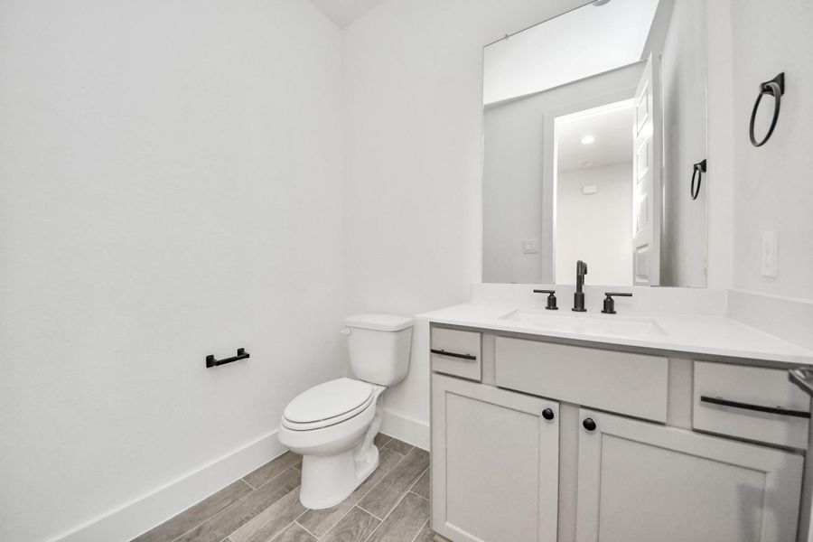 Sophisticated half bathroom adorned with contemporary finishes. The elegant 5-panel door welcomes you to a space where style meets functionality. Notice the sleek hardware accents that add a touch of modern charm. The vanity boasts light-colored countertops, beautifully complemented by a tasteful vanity light, creating a well-lit and inviting atmosphere. Sophisticated half bathroom adorned with contemporary finishes. The elegant 5-panel door welcomes you to a space where style meets functionality. Notice the sleek hardware accents that add a touch of modern charm. The vanity boasts light-colored countertops, beautifully complemented by a tasteful vanity light, creating a well-lit and inviting atmosphere.