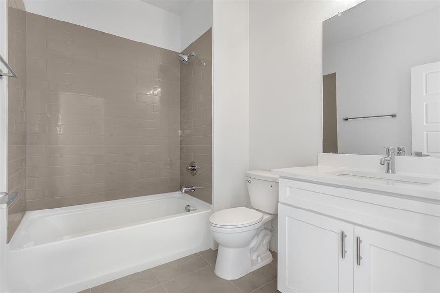 Full bathroom with vanity, tile patterned flooring, tiled shower / bath combo, and toilet