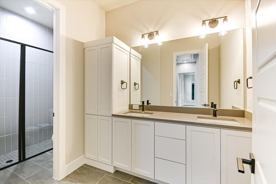 Bathroom with double vanity, a stall shower, and light tile patterned floors