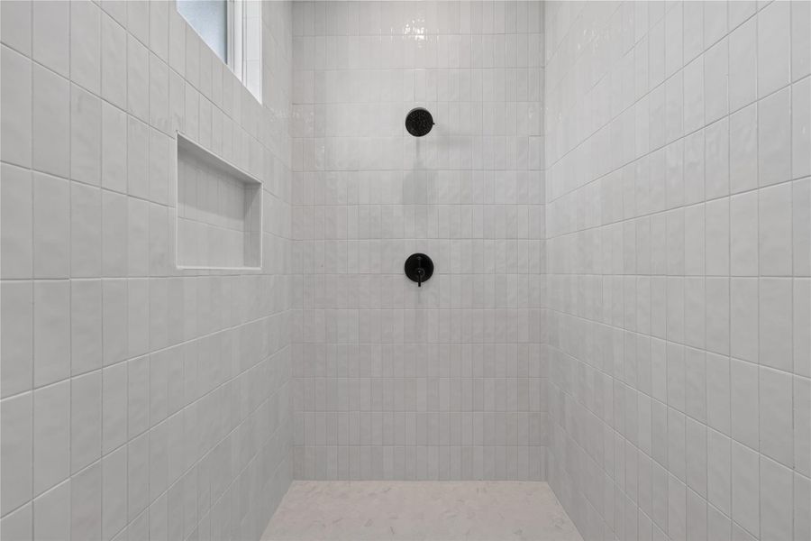 Floor-to-ceiling tiling and matte black fixtures define this minimalist walk-in shower design.