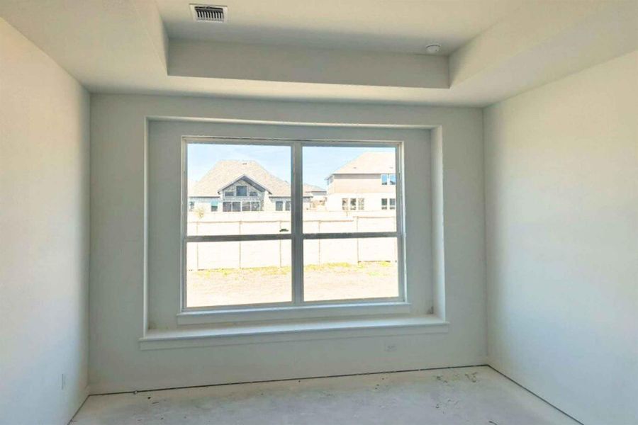 Empty room featuring unfinished concrete flooring and a tray ceiling