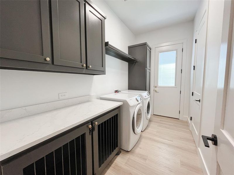 Laundry area featuring light wood-style flooring, washer and clothes dryer, and cabinet space