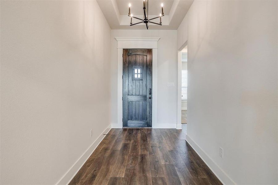 Entrance foyer featuring dark wood-type flooring and a notable chandelier