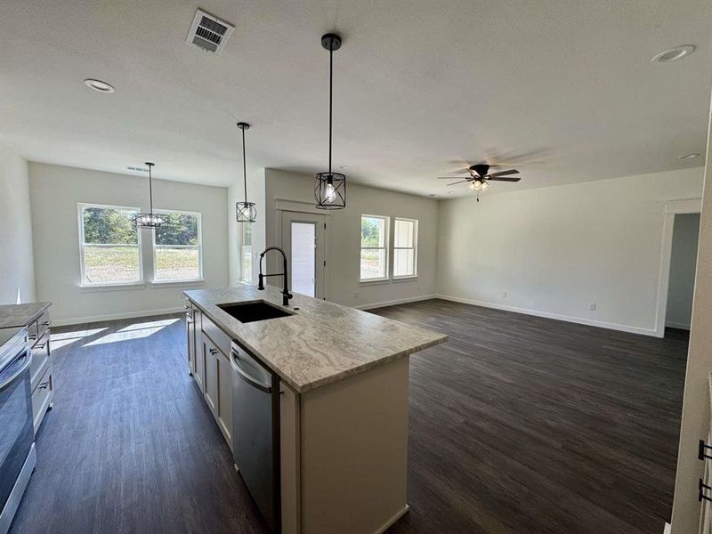 Kitchen with a kitchen island with sink, pendant lighting, dark wood-style flooring, open floor plan, and recessed lighting Kitchen with a kitchen island with sink, pendant lighting, dark wood-style flooring, open floor plan, and recessed lighting