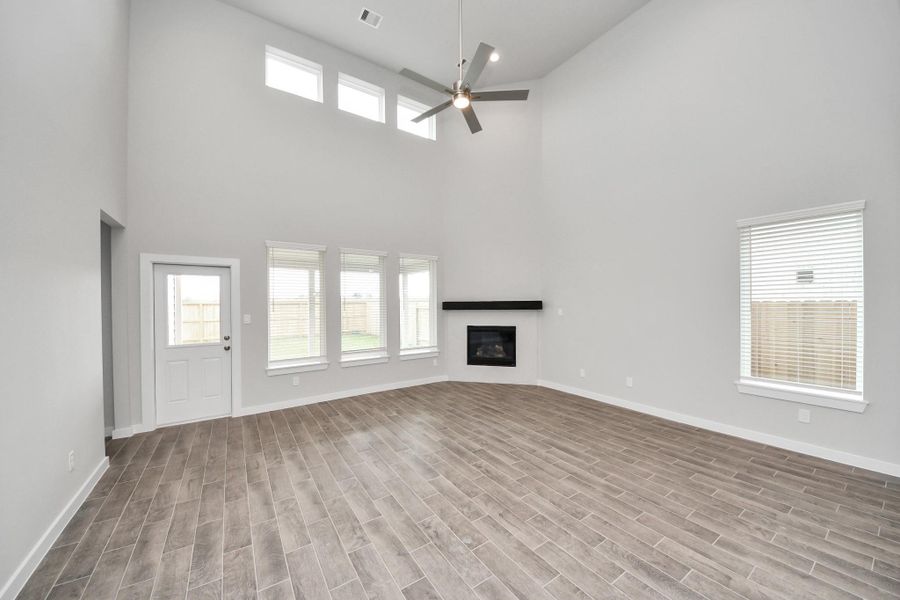 Relax and unwind in this inviting family room, illuminated by abundant natural light streaming in through tall windows, complemented by high ceilings and stunning flooring. Stay comfortable year-round with the gentle breeze from the ceiling fan, creating the perfect atmosphere for family gatherings. Sample photo of completed home with similar floor plan. Actual colors and selections may vary.
