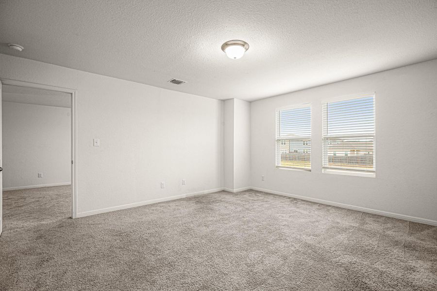 Empty room with a textured ceiling and light colored carpet