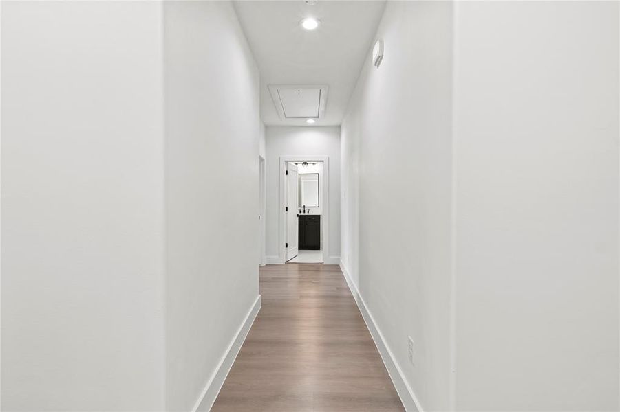 Hall featuring attic access, wood finished floors, and recessed lighting