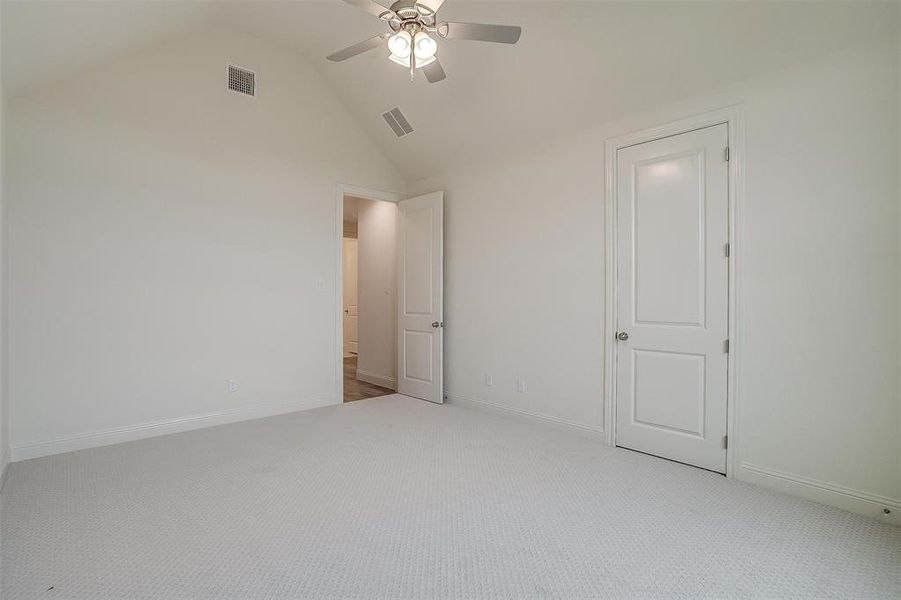 Unfurnished bedroom with lofted ceiling, light carpet, and ceiling fan