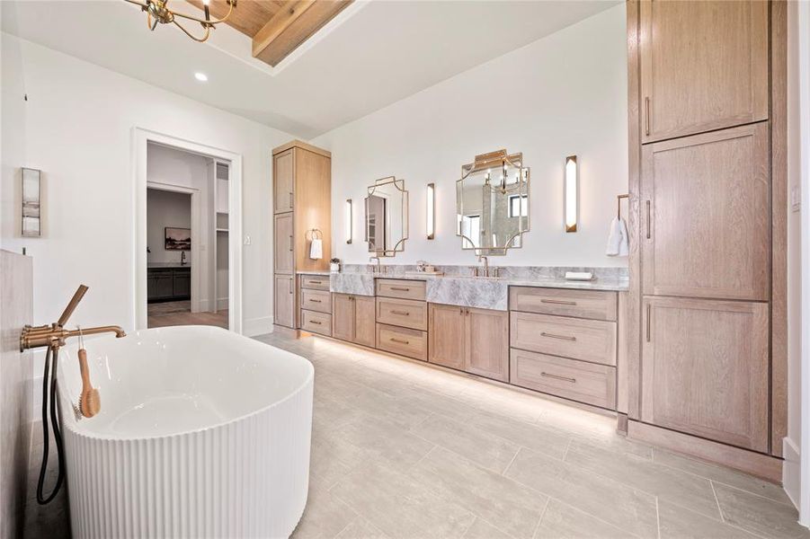 Full bath featuring a freestanding tub, double vanity, a chandelier, a walk in closet, and recessed lighting