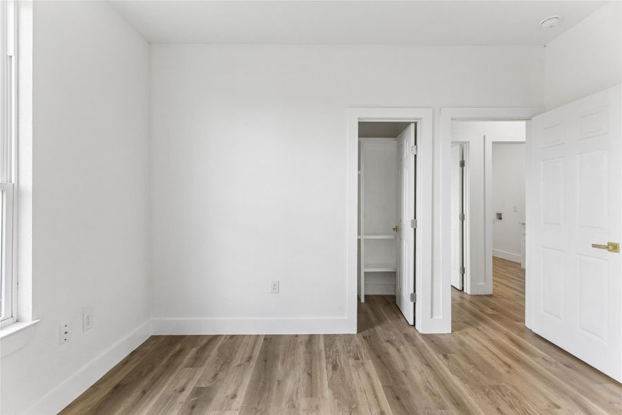 A quiet bedroom with light wood flooring provides a serene, flexible living space.