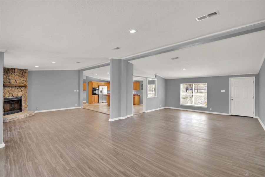 Unfurnished living room with a stone fireplace, recessed lighting, and wood finished floors