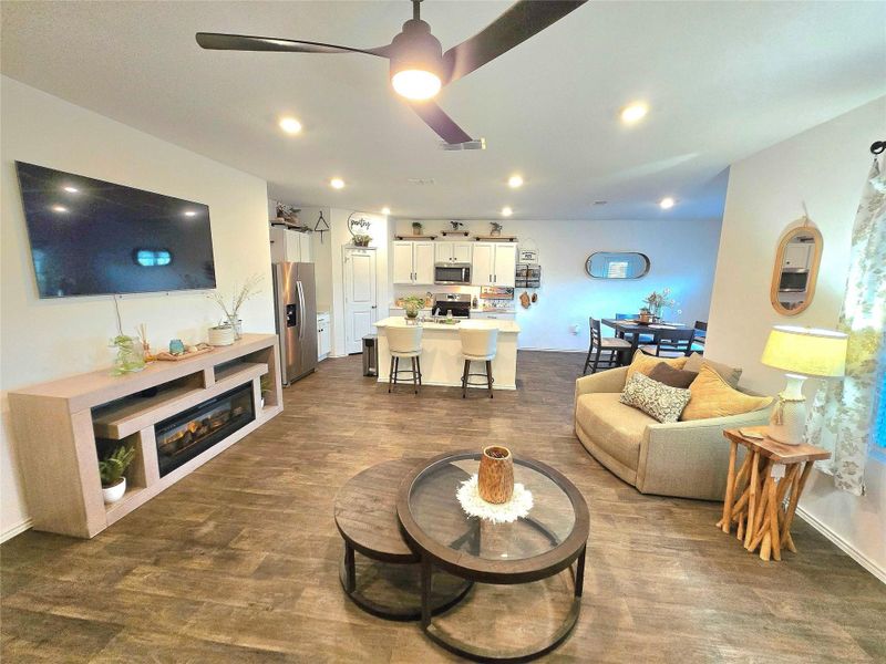 Open-concept living space featuring wood-finish flooring, recessed lighting, a ceiling fan, and a built-in media console with an electric fireplace