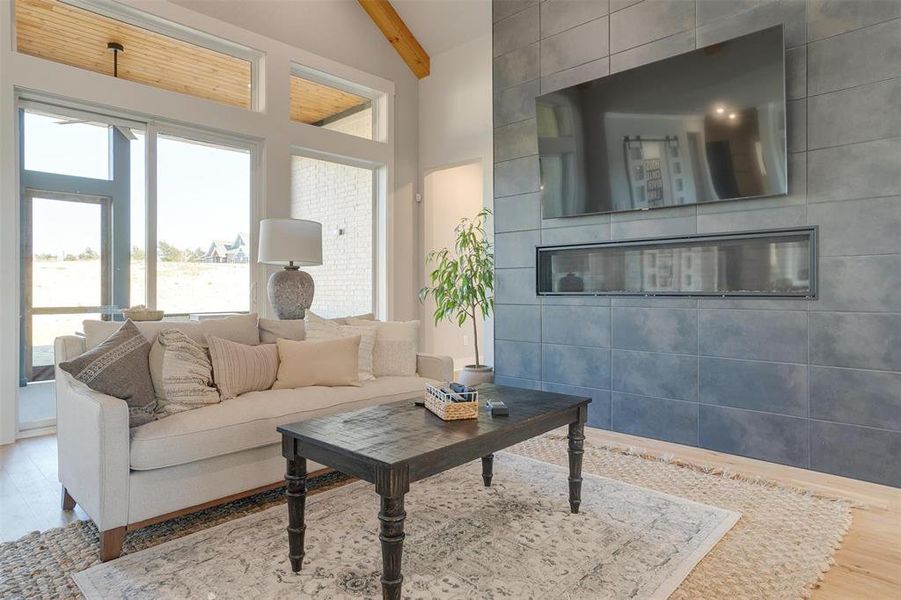 Living room with beamed ceiling, high vaulted ceiling, tile walls, and hardwood / wood-style flooring