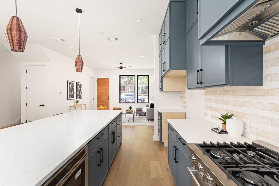 Culinary excellence awaits with a pristine kitchen island, sleek cabinetry, and integrated appliances, flowing into an inviting living area.