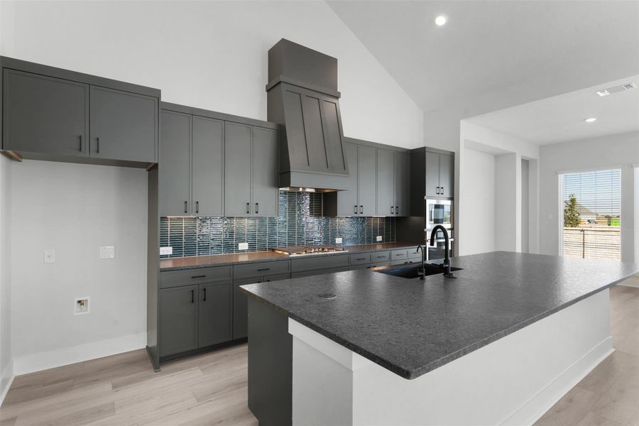 Kitchen featuring a kitchen island with sink, tasteful backsplash, light wood-style floors, gray cabinets, and recessed lighting