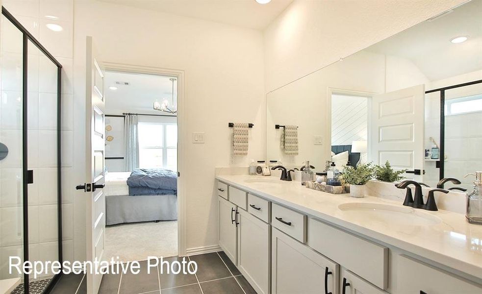 Bathroom featuring tile patterned flooring, a shower with door, vanity, and an inviting chandelier