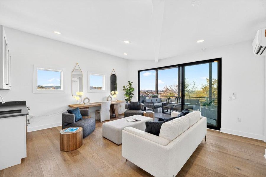 Living area featuring light wood-style flooring, recessed lighting, and a wall mounted air conditioner