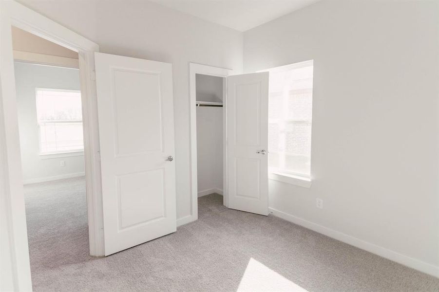 Unfurnished bedroom featuring light carpet and a closet