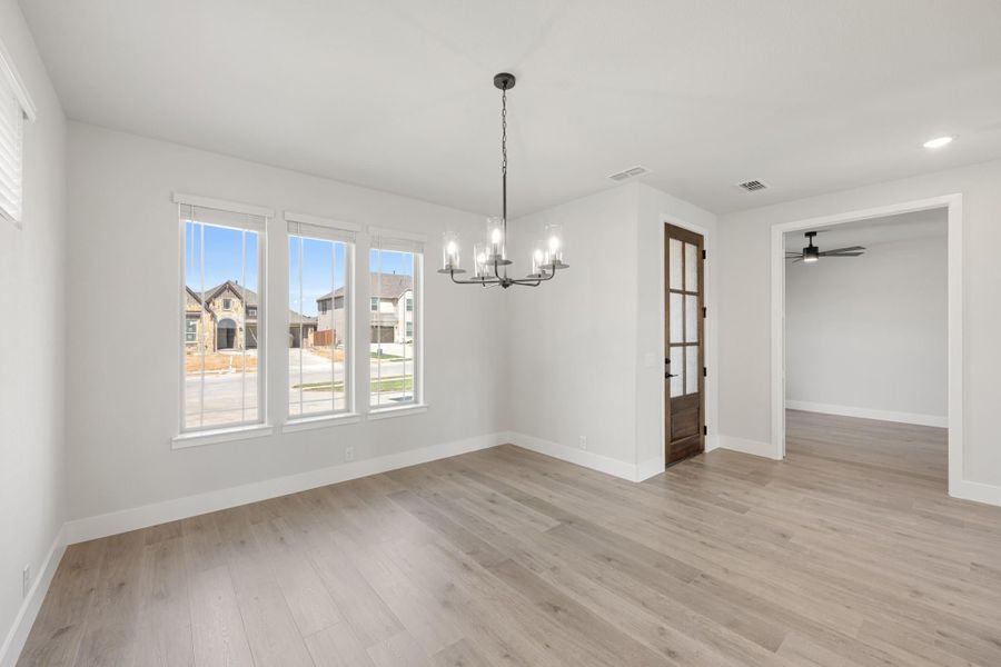 Empty dining room with light wood floors, chandelier, and wood-framed glass door Empty dining room with light wood floors, chandelier, and wood-framed glass door