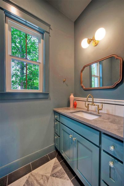 Refined powder bath features elegant gold-tone fixtures complementing the sleek vanity and patterned marble floor.
