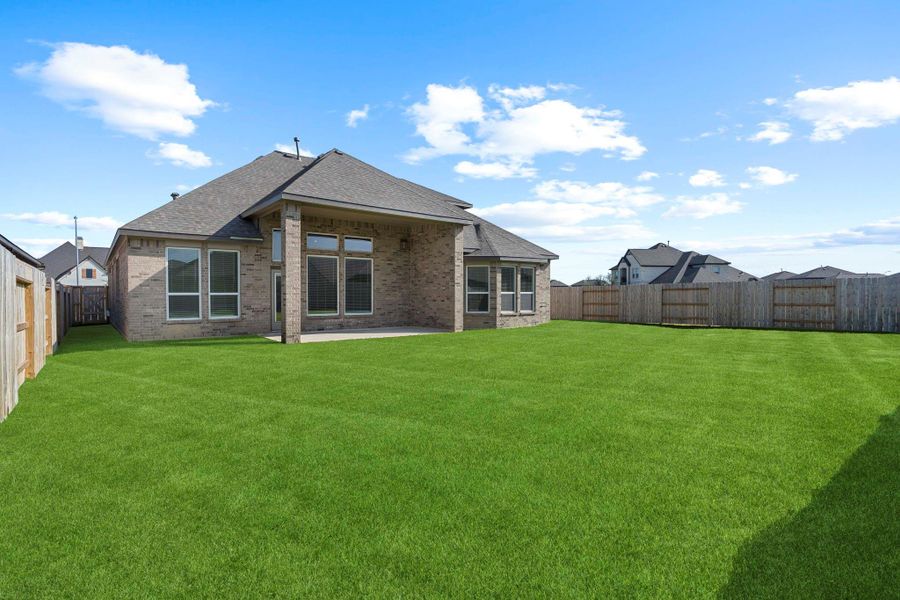 Rear exterior view highlights the covered patio, expansive windows, and large fenced backyard—perfect for outdoor living.  Almost all brick exterior for less upkeep!