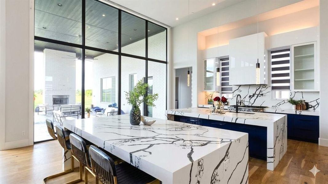 Gourmet kitchen with waterfall island, contrasting blue cabinetry, and a full-height tiled backsplash