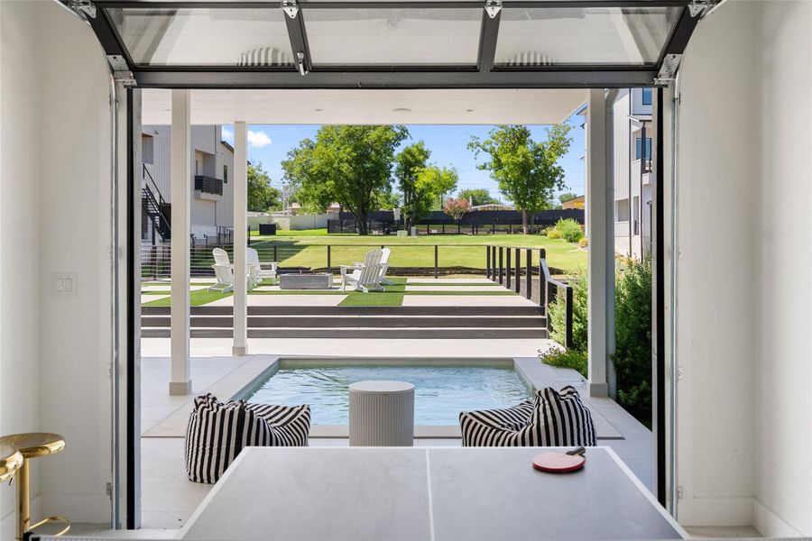 An open garage door reveals an inviting backyard oasis with a pristine pool and lush green lawn. An open garage door reveals an inviting backyard oasis with a pristine pool and lush green lawn.
