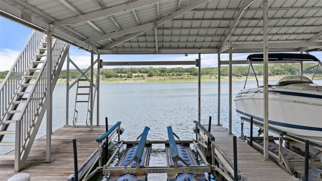 Covered boat dock featuring two boat slips, a metal roof structure, and a dedicated boat lift