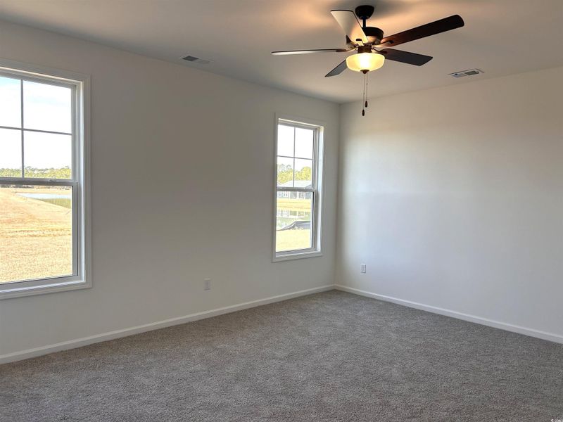 Carpeted empty room featuring a ceiling fan and baseboards