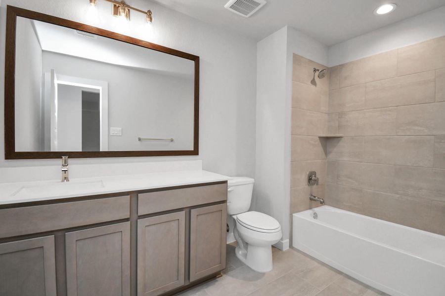 Secondary bath features tile flooring, bath/shower combo with tile surround, light stained wood cabinets, beautiful light countertop. Sample photo of completed home with similar floor plan. Actual colors and selections may vary. Secondary bath features tile flooring, bath/shower combo with tile surround, light stained wood cabinets, beautiful light countertop. Sample photo of completed home with similar floor plan. Actual colors and selections may vary.