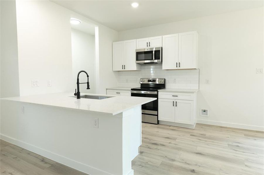 Kitchen with sink, white cabinetry, appliances with stainless steel finishes, and kitchen peninsula