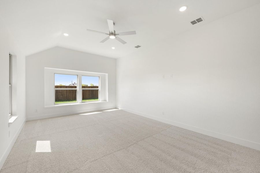 Empty bedroom with vaulted ceiling, ceiling fan, carpet flooring, and double windows