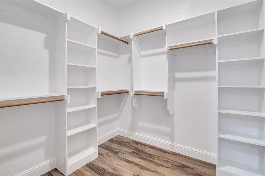 Walk in closet with hardwood / wood-style flooring