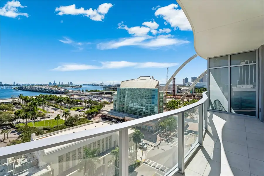 Covered balcony featuring tile flooring and a glass panel railing
