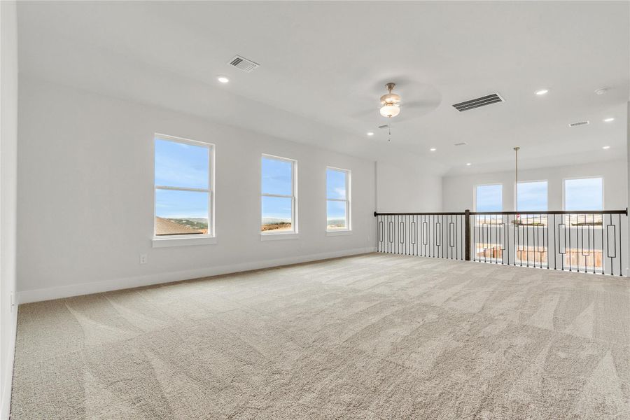 A spacious upper-level area offers multiple windows and plush carpet.