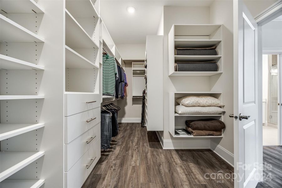 This roomy primary closet has been updated with wood shelving and storage areas.