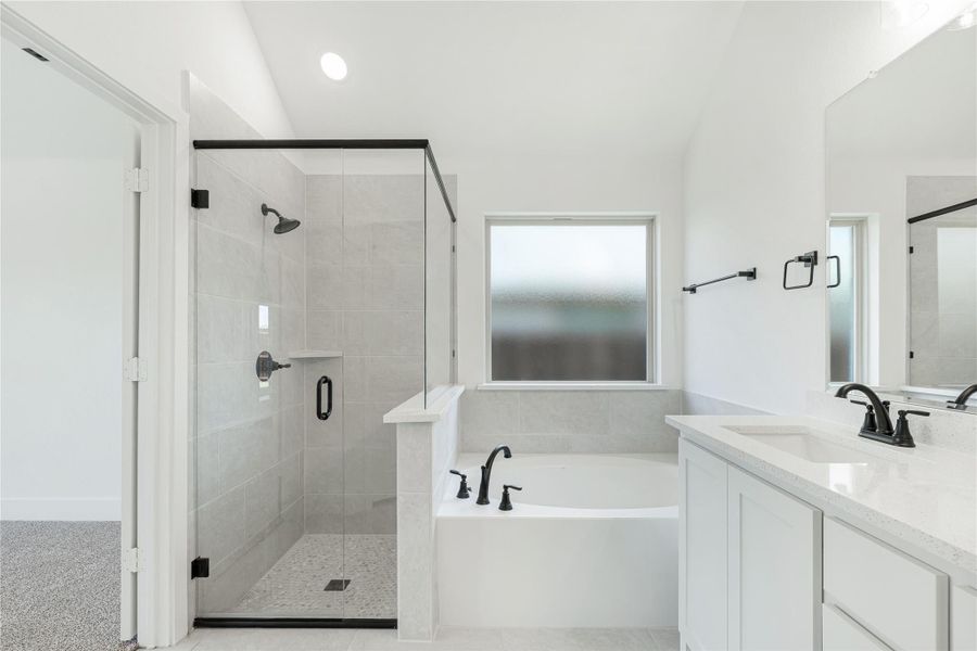Master bathroom with glass walk-in shower, soaking tub, and white double vanity with black fixtures