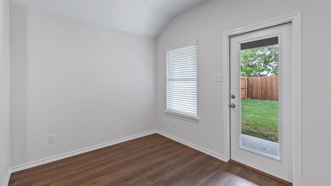 Doorway with vaulted ceiling and wood finished floors