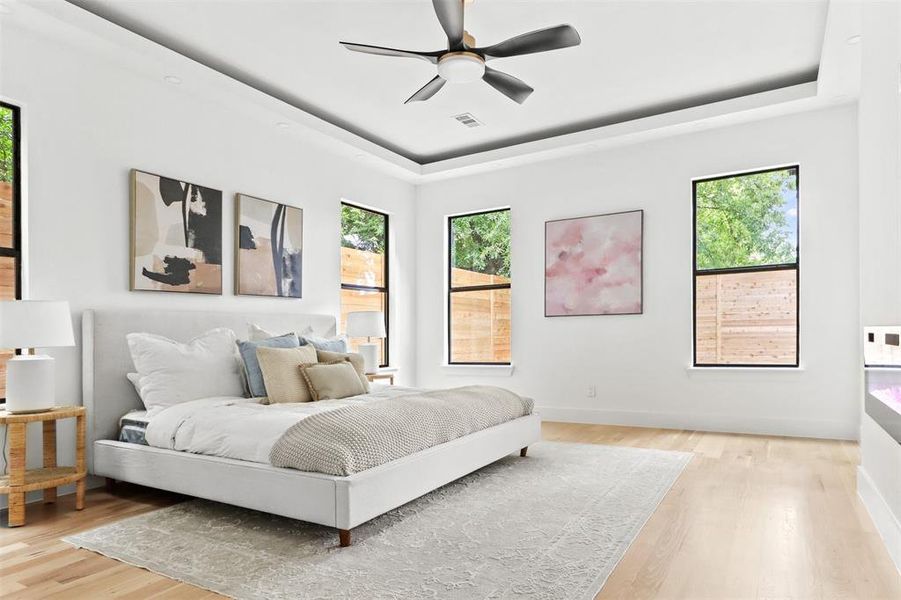 Bedroom with a tray ceiling, ceiling fan, and light hardwood / wood-style floors